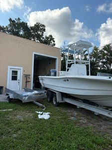 Boat trailer with white fishing boat and storage unit on grassy lot