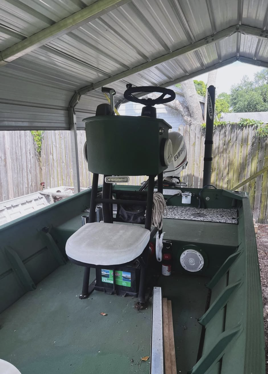 Green golf cart parked in covered carport with steering wheel and control panel visible