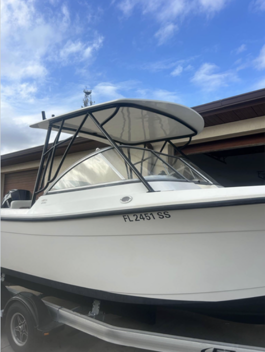 White recreational fishing boat with black T-top canopy and Florida registration number FL2451SS