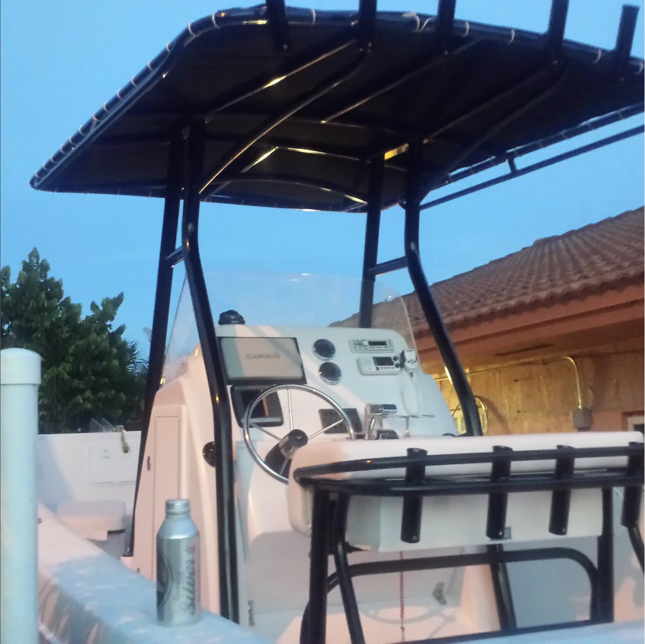 Boat helm station with steering wheel and control panels under black T-top canopy