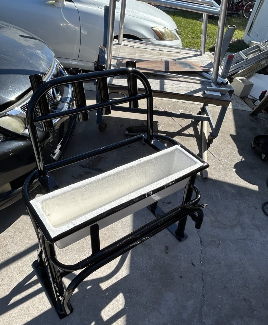 Black metal utility cart with white interior bed displayed outdoors in parking lot