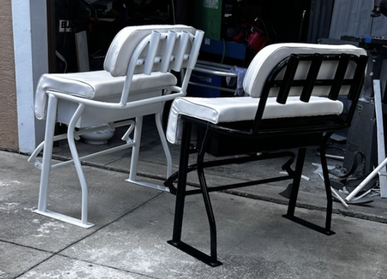 Two modern stackable lounge chairs displayed outdoors, one white and one black, positioned on a concrete surface