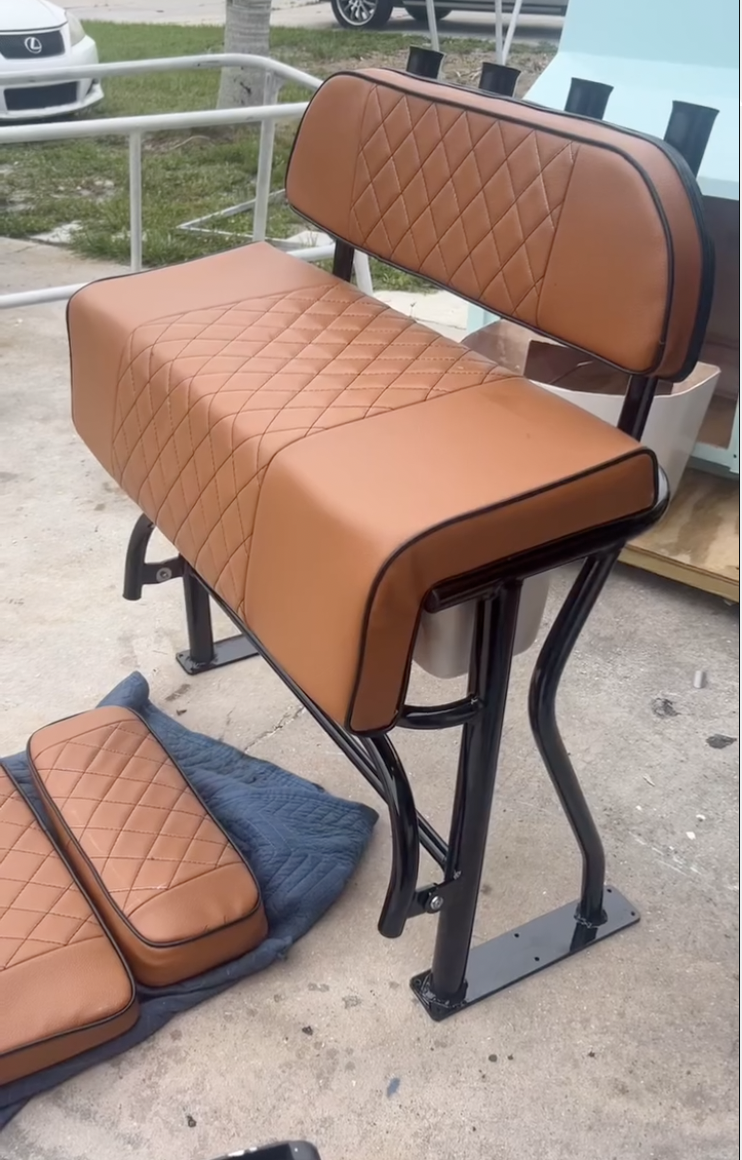 Golf cart seat with tan quilted upholstery and black frame displayed outdoors