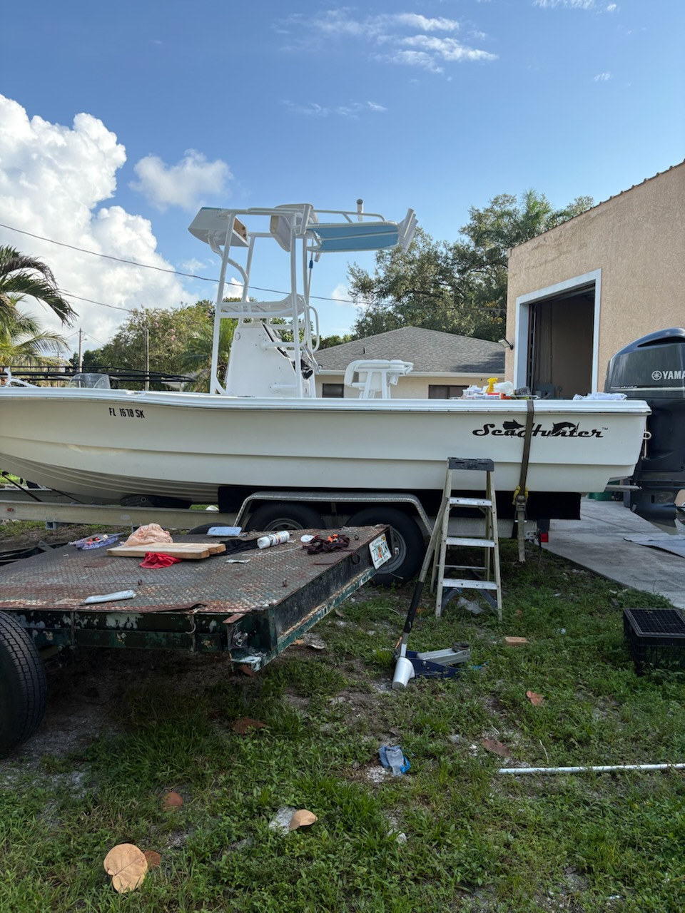 White Saltwater fishing boat on trailer with T-top and Yamaha motor in residential driveway