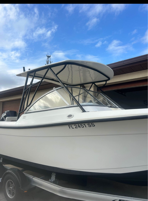 White recreational fishing boat with black bimini top and registration FL2451SS on trailer