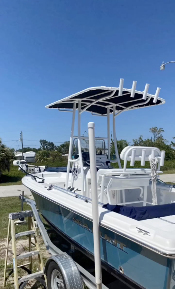 White center console fishing boat with T-top canopy on trailer