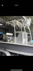 White boat with T-top canopy displayed on black trailer bed