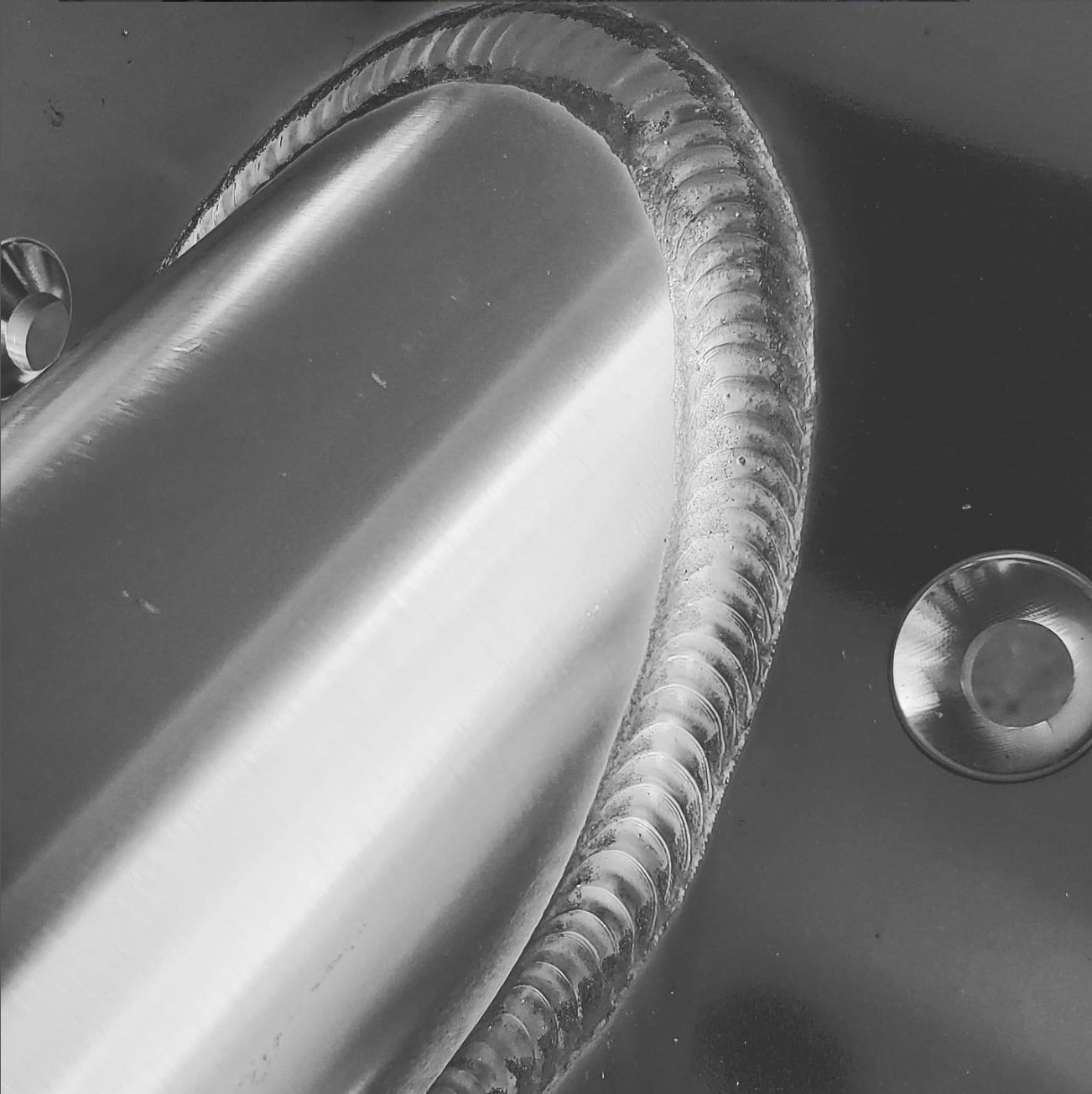 Close-up of curved metal pipe with textured ribbed exterior and smooth interior surface