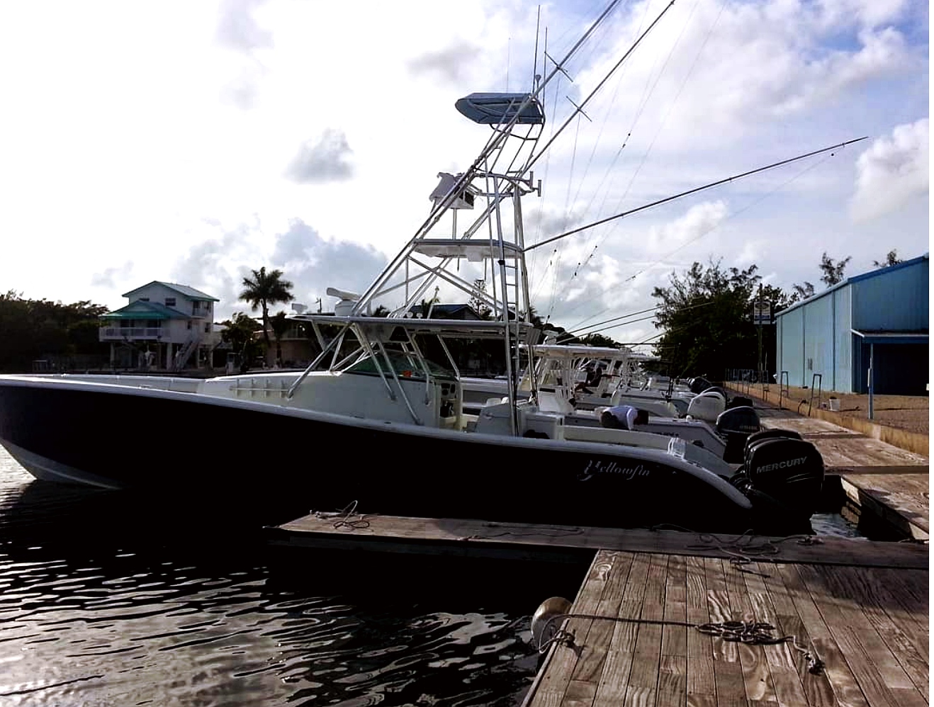Sport fishing boat docked at wooden pier with Mercury outboard motors